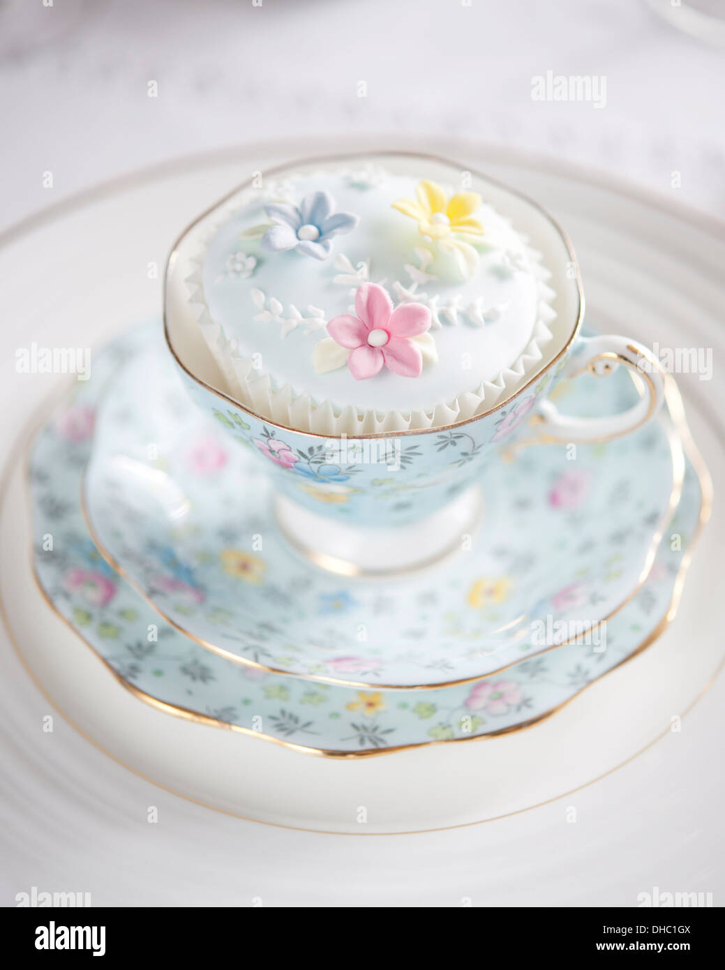 Eine florale China Tasse, Untertasse und Teller, mit vereisten cupcake Stockfoto