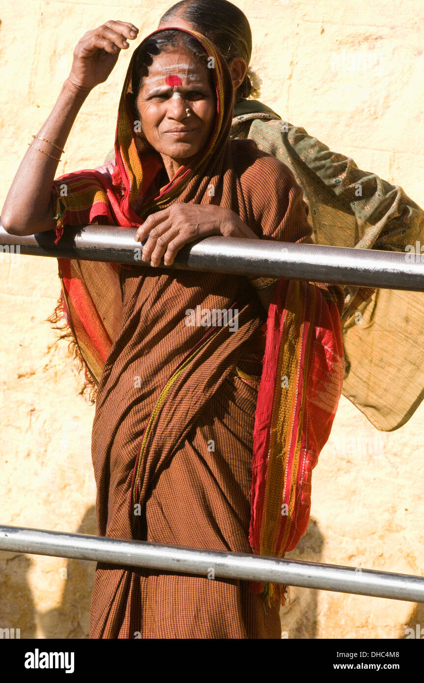 Südindische Frau wartet am Straßenrand durch Geländer in einer braunen Sari mit traditionellen heilige Asche und Safran RedDot Stockfoto