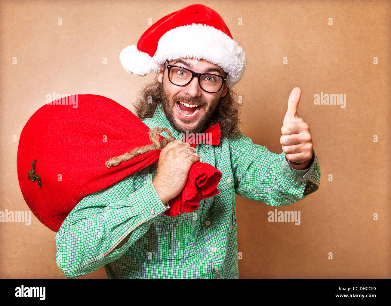Santa Claus mit einer Tasche von Geschenken Blick in die Kamera und zeigt Anzeichen von cool Stockfoto