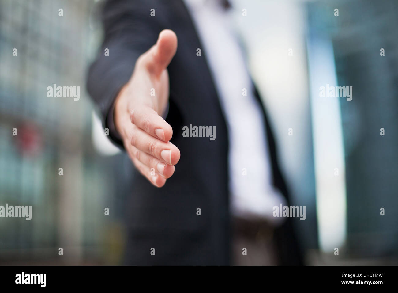 Geschäftsmann bietet für Handshake auf Office-Gebäude-Hintergrund Stockfoto