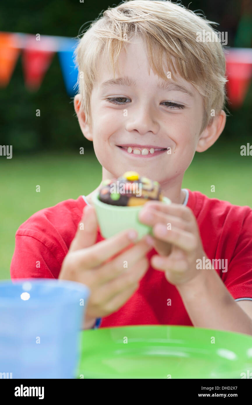 Fröhlicher Junge Essen Muffin auf einer Geburtstagsfeier Stockfoto