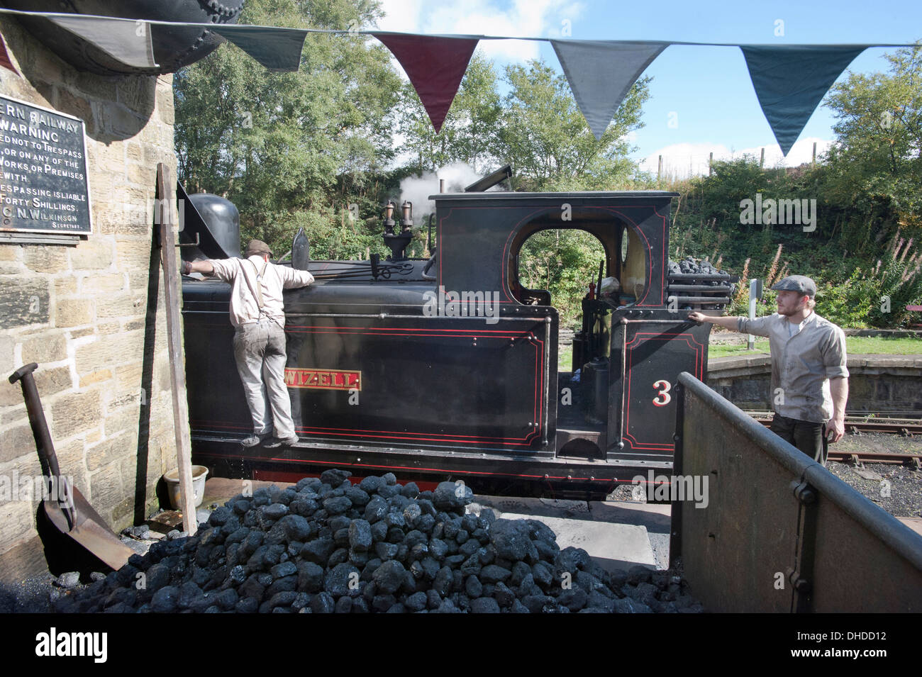 Der Feuerwehrmann der ehemaligen Coal Board Tank Motor Dampf Lok Nr. 3 "Twizell" Tanks mit Wasser füllt, als der Fahrer auf Andrews House Station auf die Tanfield Eisenbahn, die Welten ältesten Eisenbahn - Pferd gezogen, in der Grafschaft Durham anschaut. Stockfoto