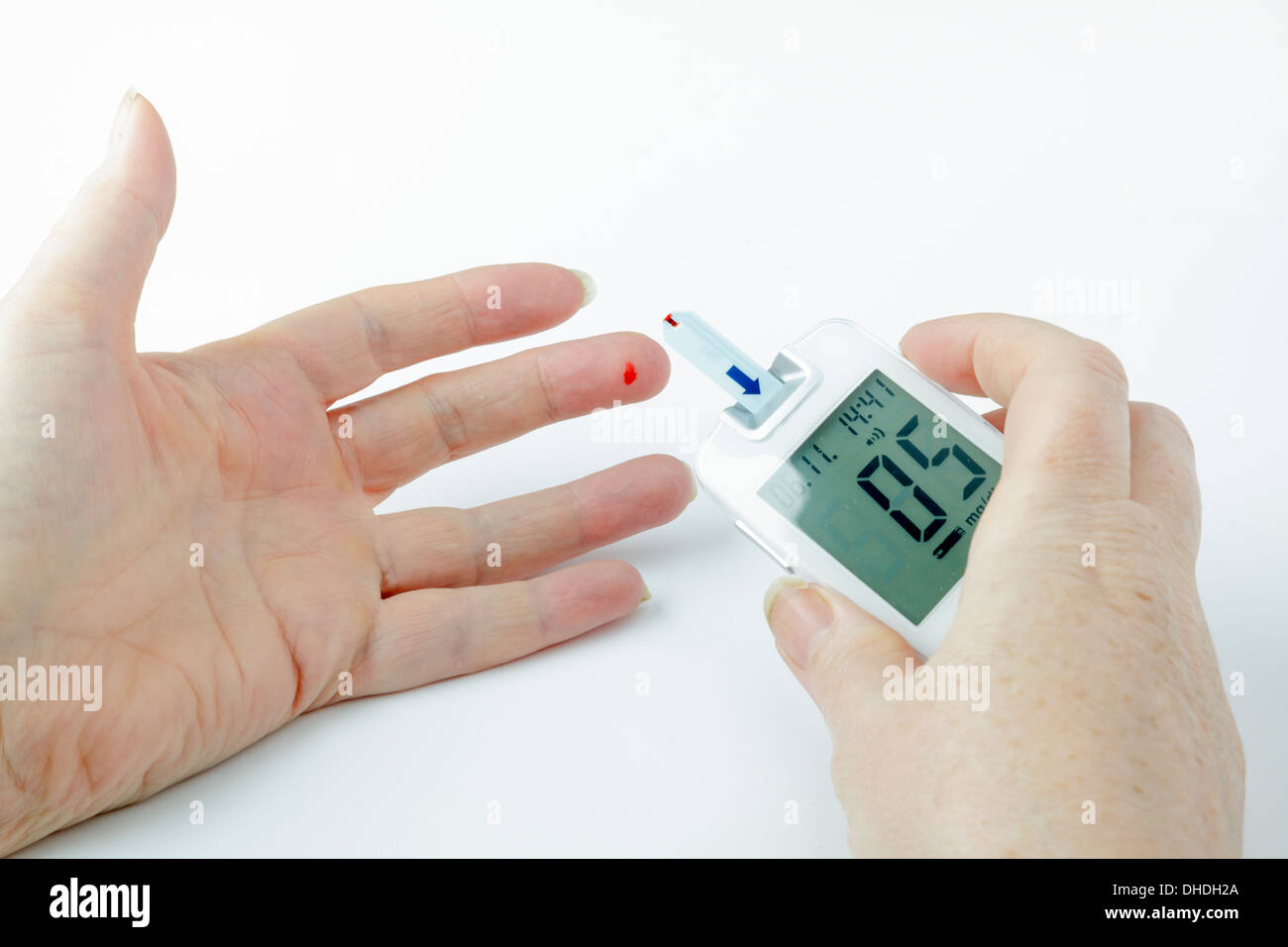 Diabetische Blutzuckermessung - Blut am Finger-Tipp und Meter-Streifen Stockfoto