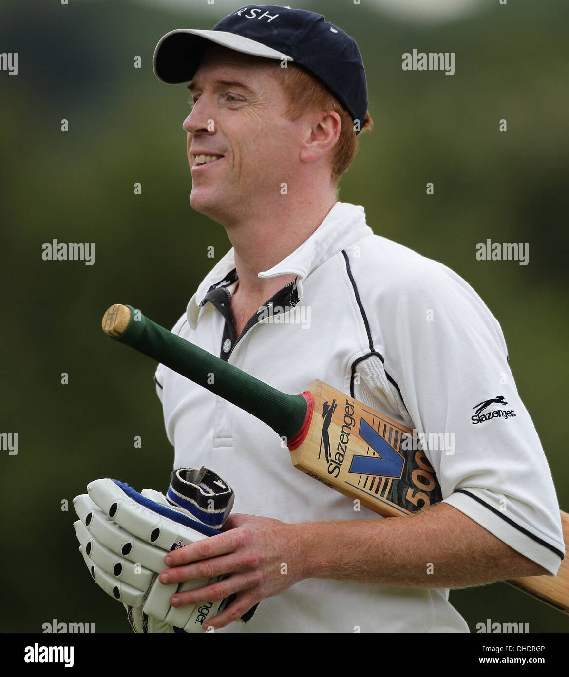 Schauspieler Damian Lewis geht das Cricket-Spielfeld mit seinen Cricket-Handschuhe und seinen Schläger versteckt unter dem Arm. Stockfoto