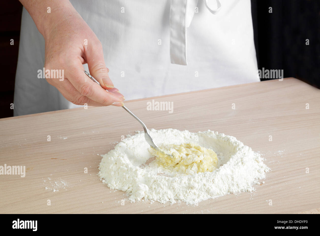 Ei dem Einrühren in Mehl auf Arbeitsfläche Stockfoto