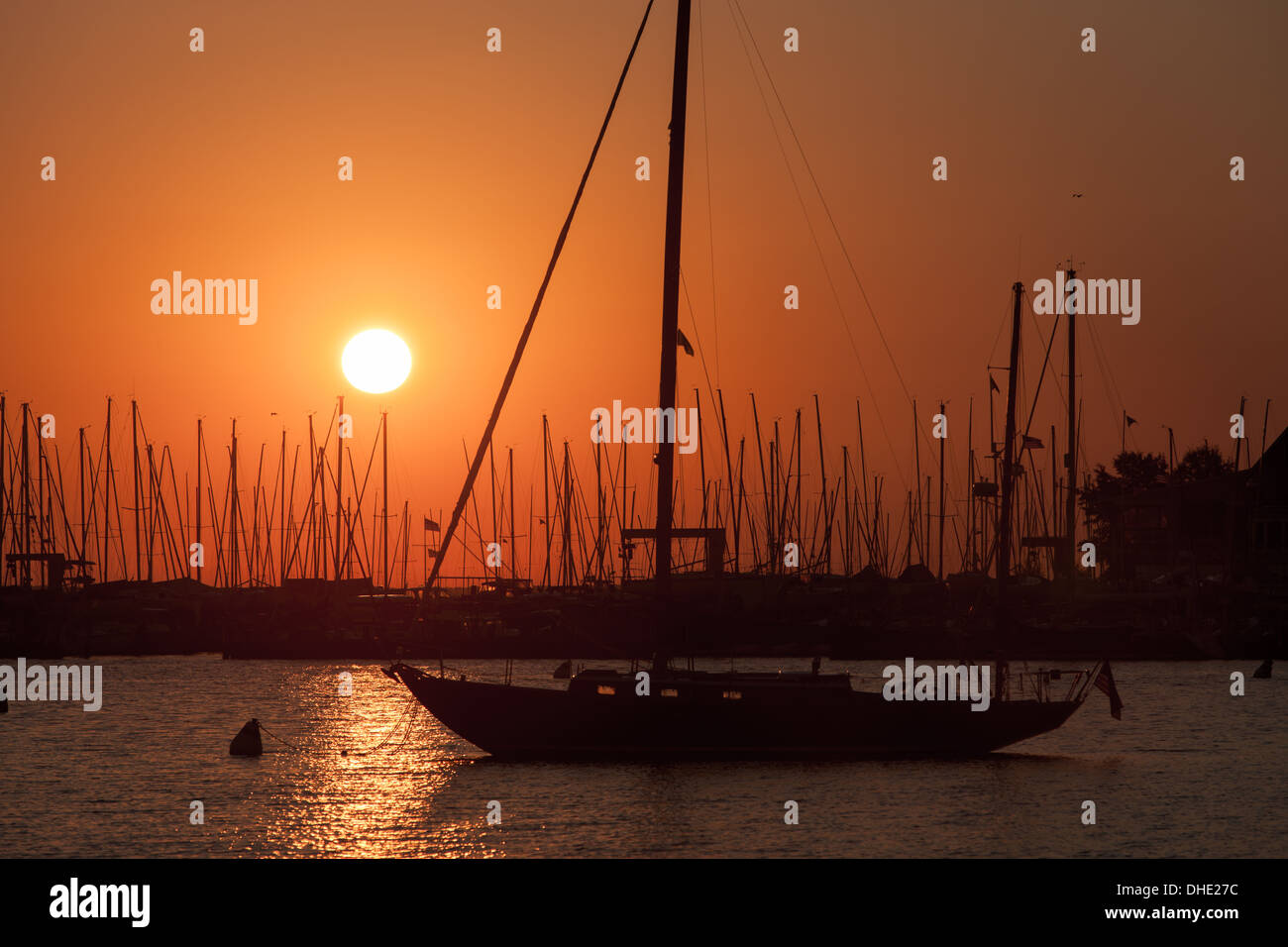 Die aufgehende Sonne dreht den Himmel orange Segelboote und andere Sportboote angedockt im Hafen in Annapolis, Maryland. Stockfoto