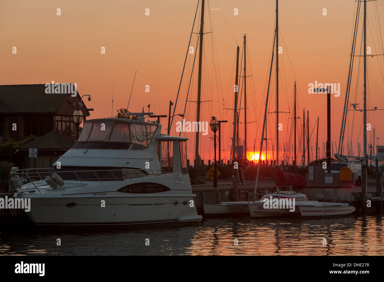 Die aufgehende Sonne dreht den Himmel orange Segelboote und andere Sportboote angedockt im Hafen in Annapolis, Maryland. Stockfoto