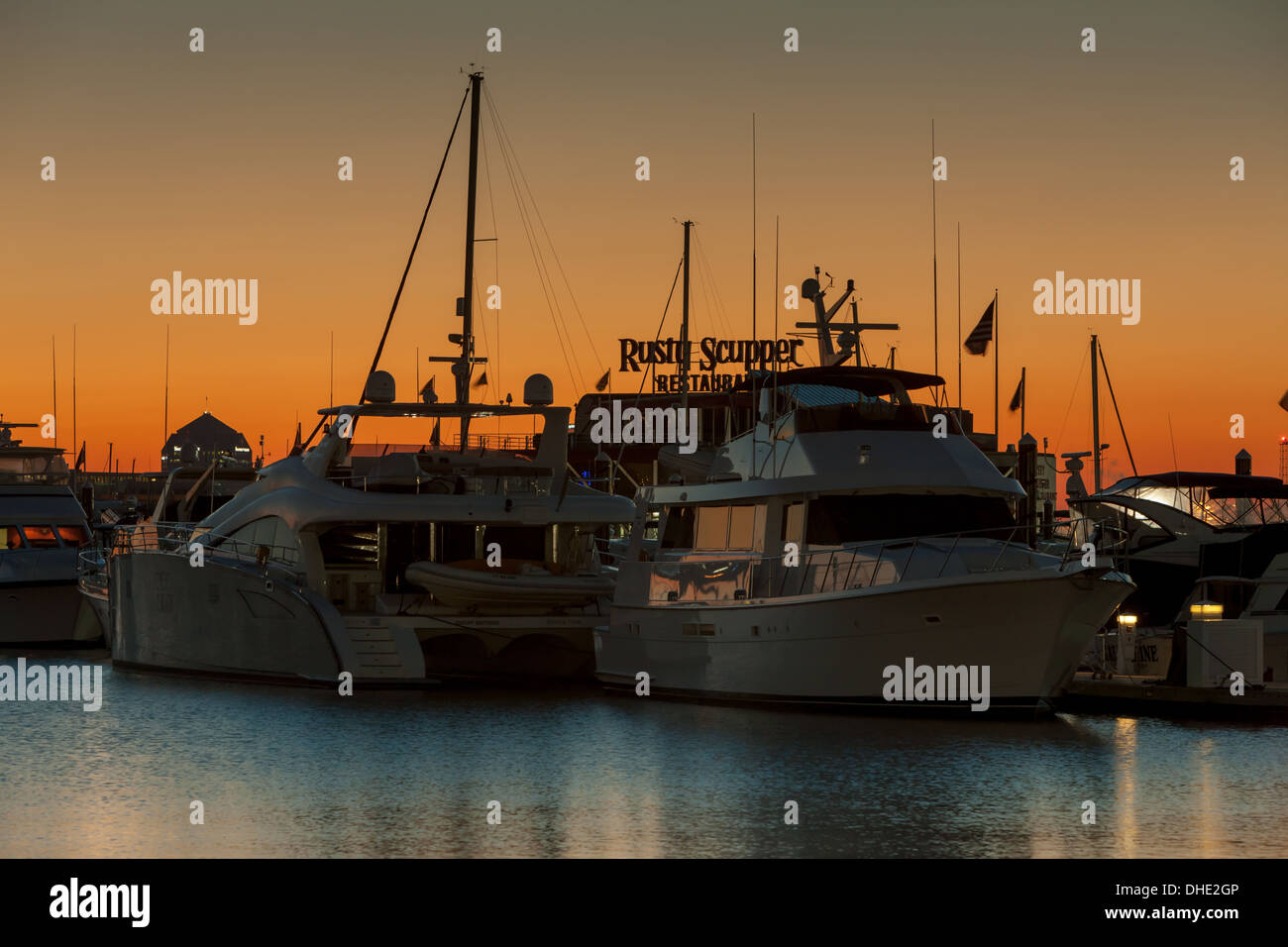 Vor Sonnenaufgang Himmel leuchtet Orange hinter Sportboote in einem der Häfen in den inneren Hafen von Baltimore, Maryland angedockt. Stockfoto