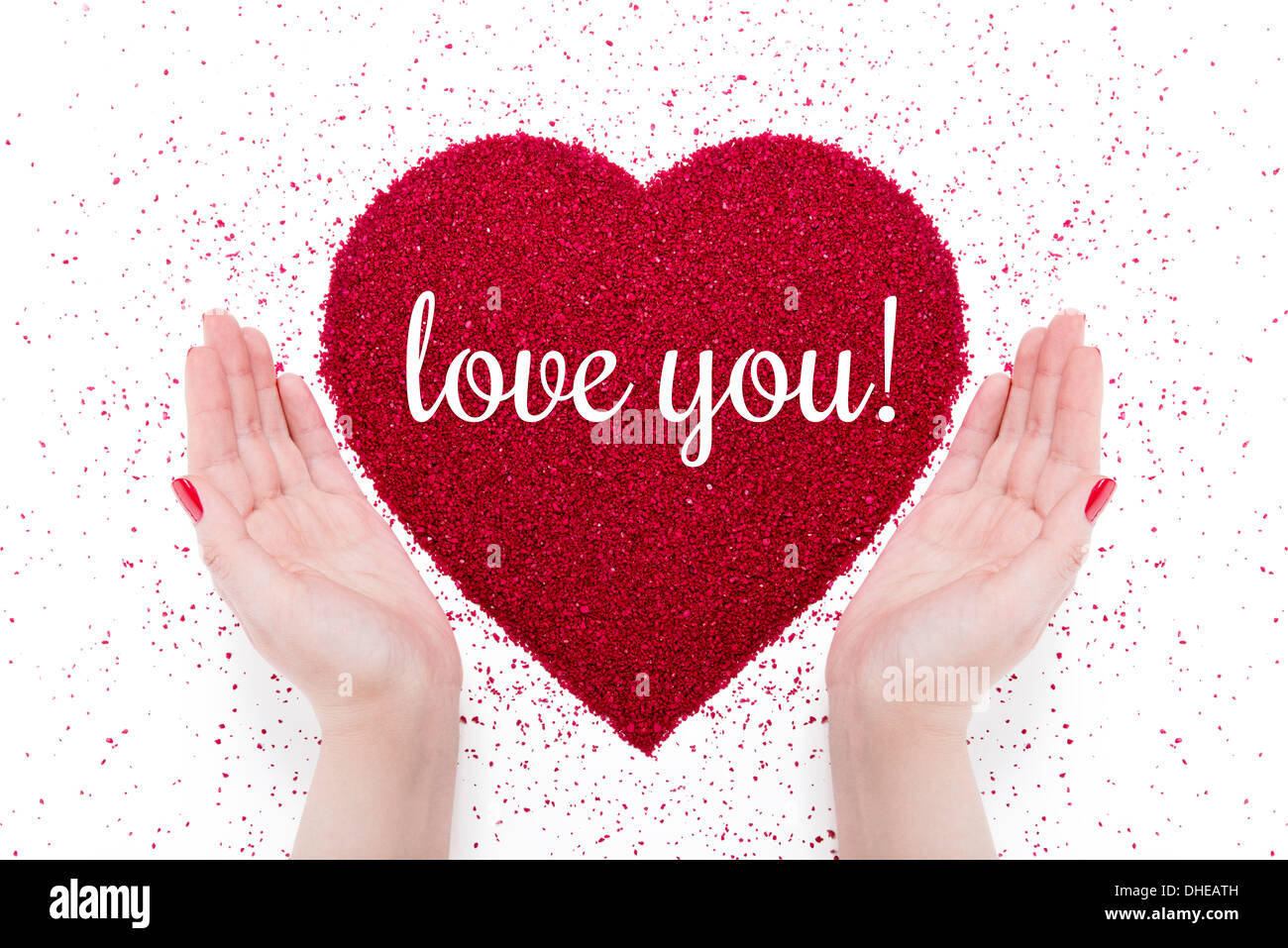 Auf das rote Herz der "Liebe Sand schriftliche dich" gemacht. Nähe befinden sich die Hände von Frauen mit roten Maniküre. Stockfoto