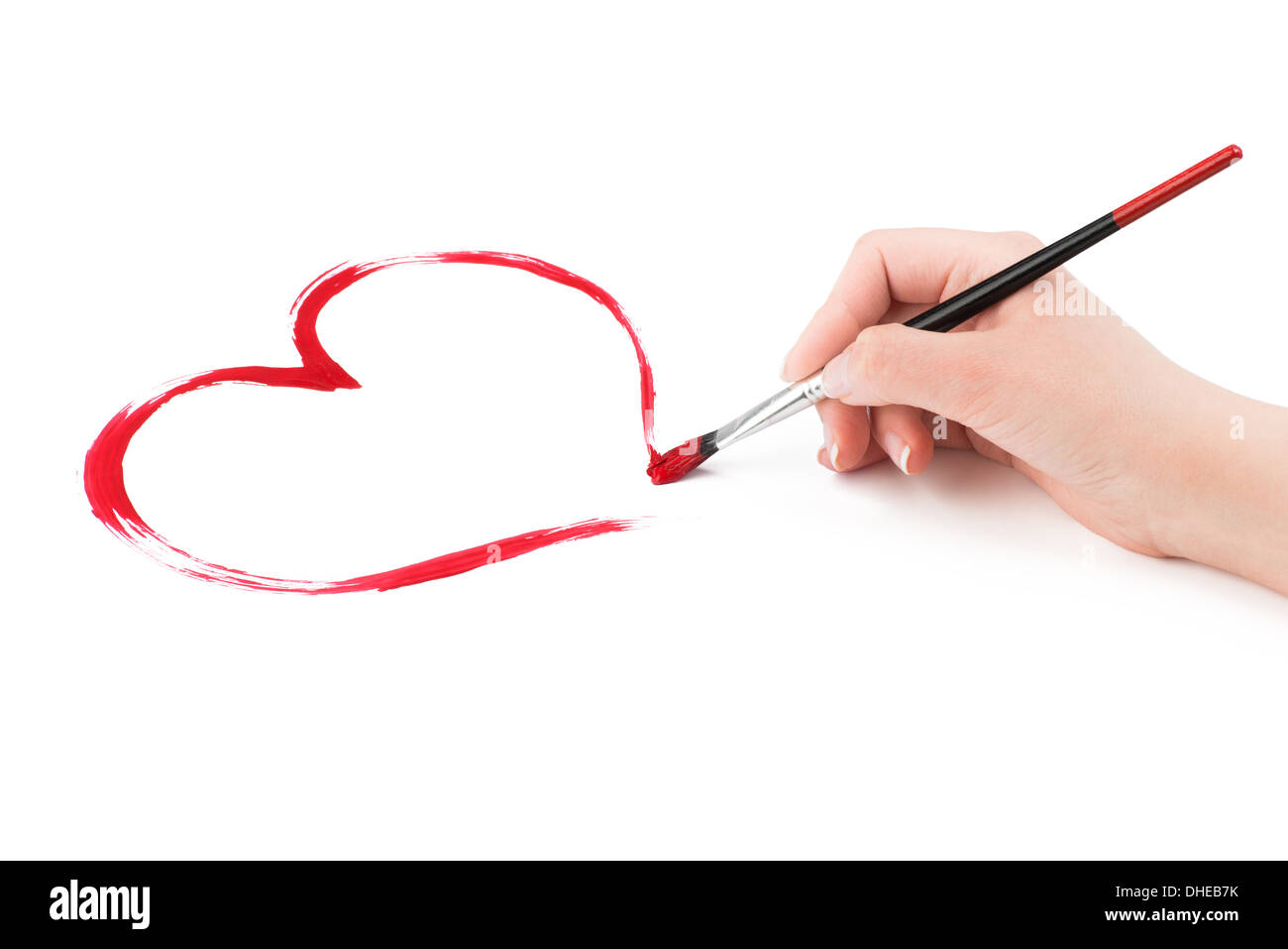 Zarte Frauenhand zieht eine rotes Herz-Form mit einem Pinsel auf einem weißen Hintergrund. Stockfoto