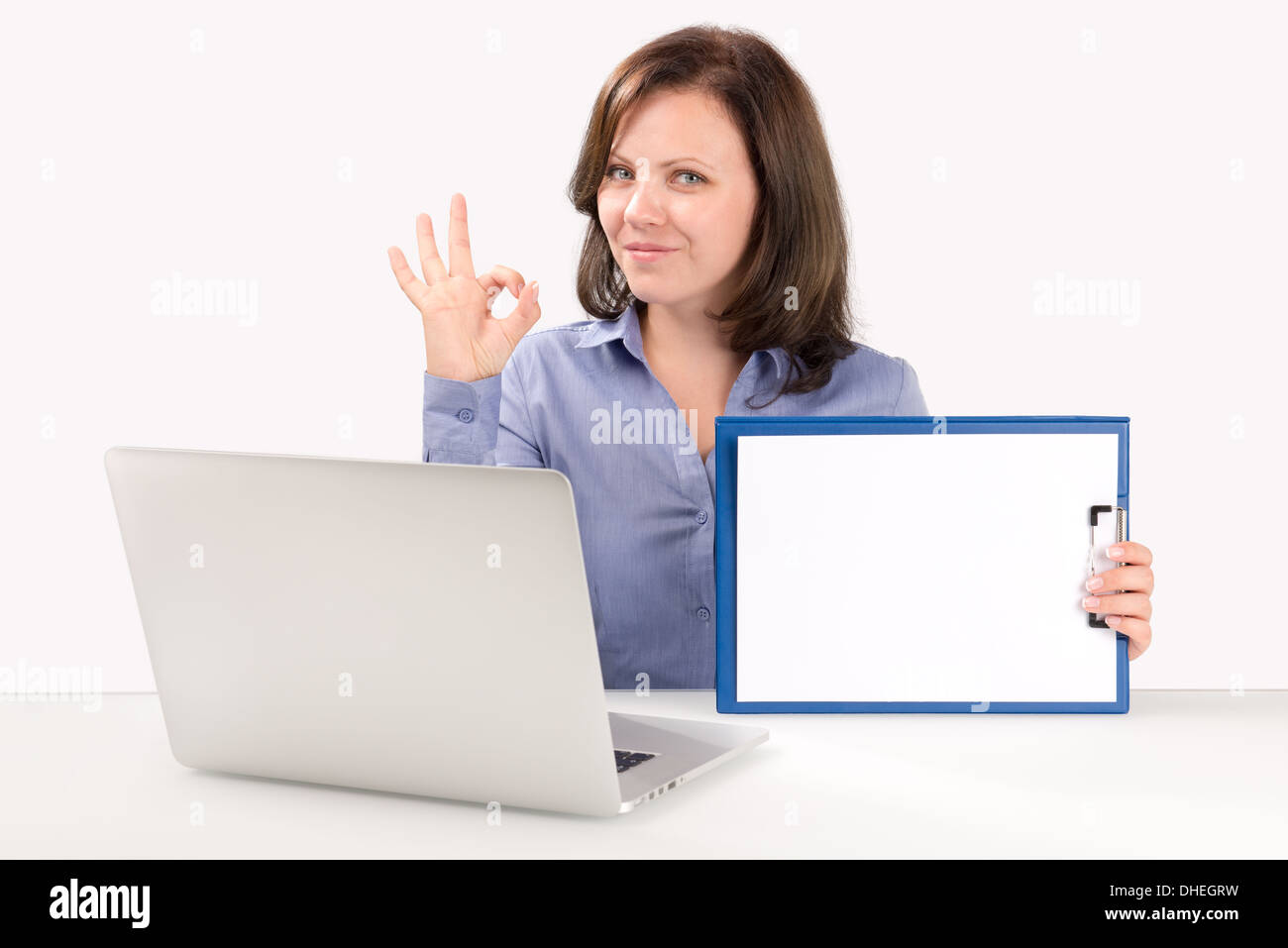 Geschäftsfrau ist sitzt vor einem modernen Laptop mit einer leeren Zwischenablage und zeigt ok Geste, Business-Konzept Stockfoto
