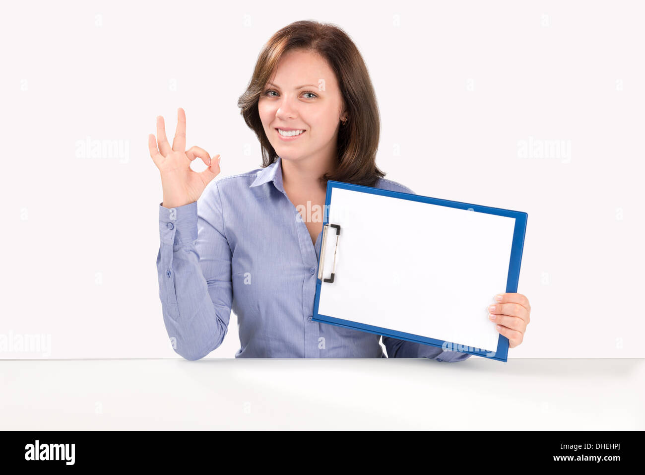 Lächelnde Geschäftsfrau hält eine leere Zwischenablage und zeigt ok Geste, Business-Konzept Stockfoto