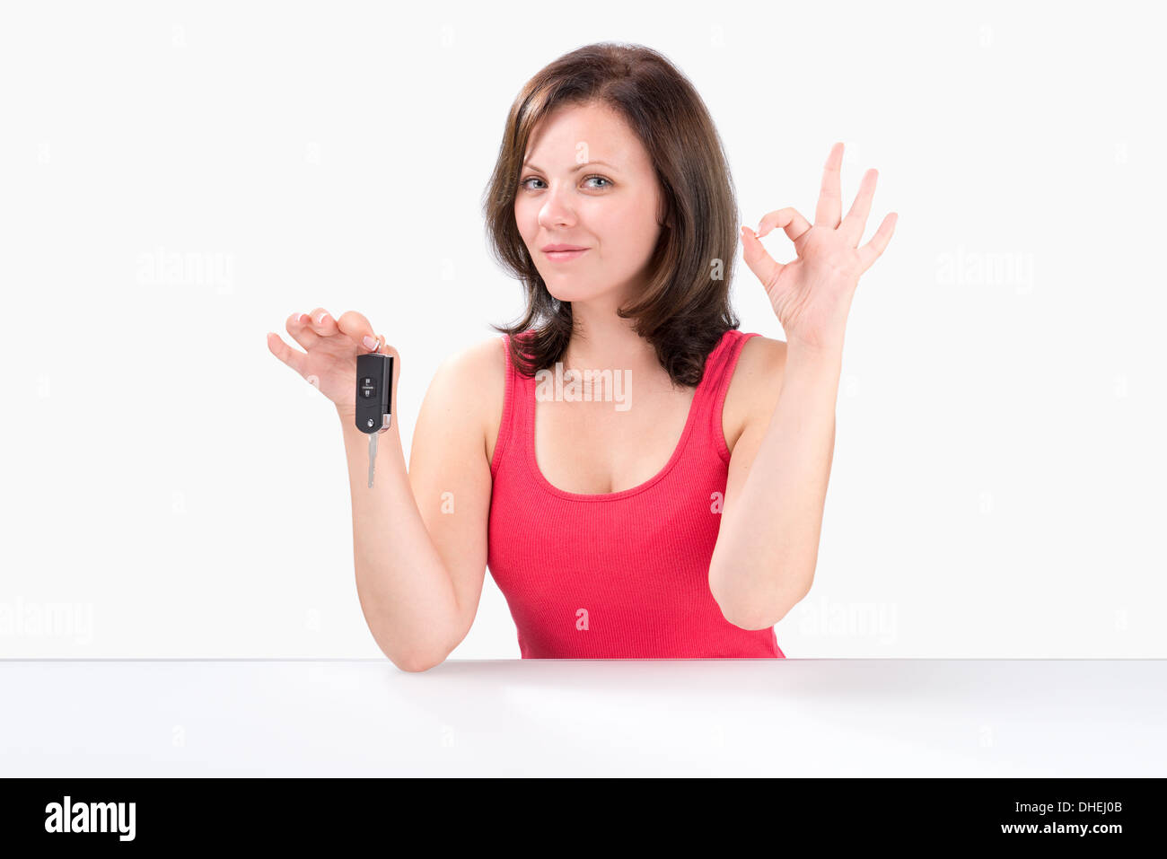 Glückliche junge Frau hält Autoschlüssel, Ordnung Geste zeigen und schaut in die Kamera Stockfoto