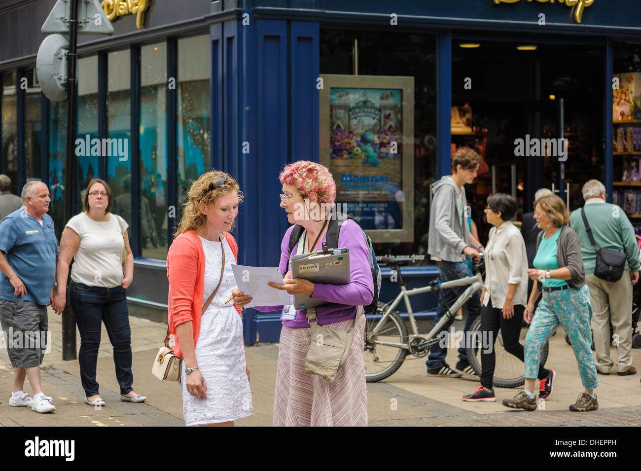 Eine Frau mittleren Alters mit einem Klemmbrett dabei eine Umfrage auf einer anderen erwachsenen Frau in einer UK-Innenstadt. Stockfoto