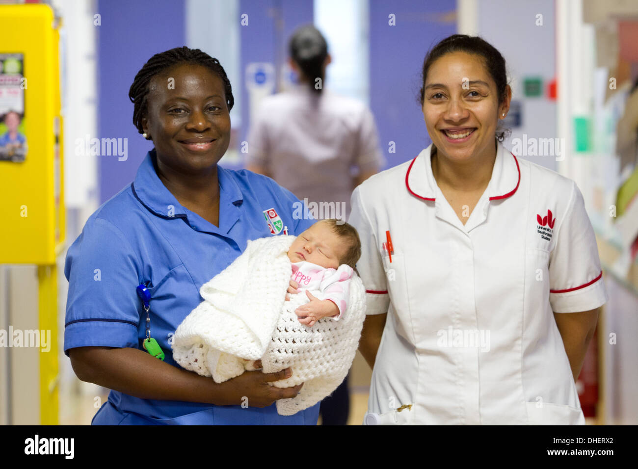 Eine Hebamme hält ein neues Baby geboren mit einer Studentin Hebamme suchen auf UK Stockfoto