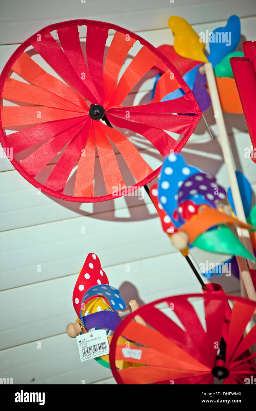 Kinder bunte bunte Meer Spielzeug Windmühlen gegen helle weiße Holzwand Stockfoto