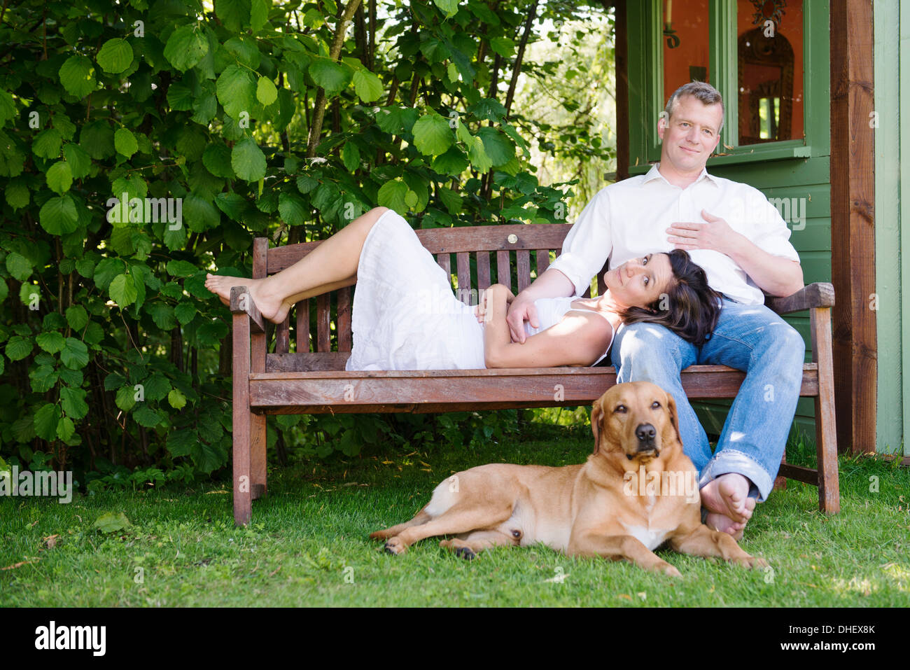 Porträt von älteres Paar auf Gartenbank mit Hund Stockfoto