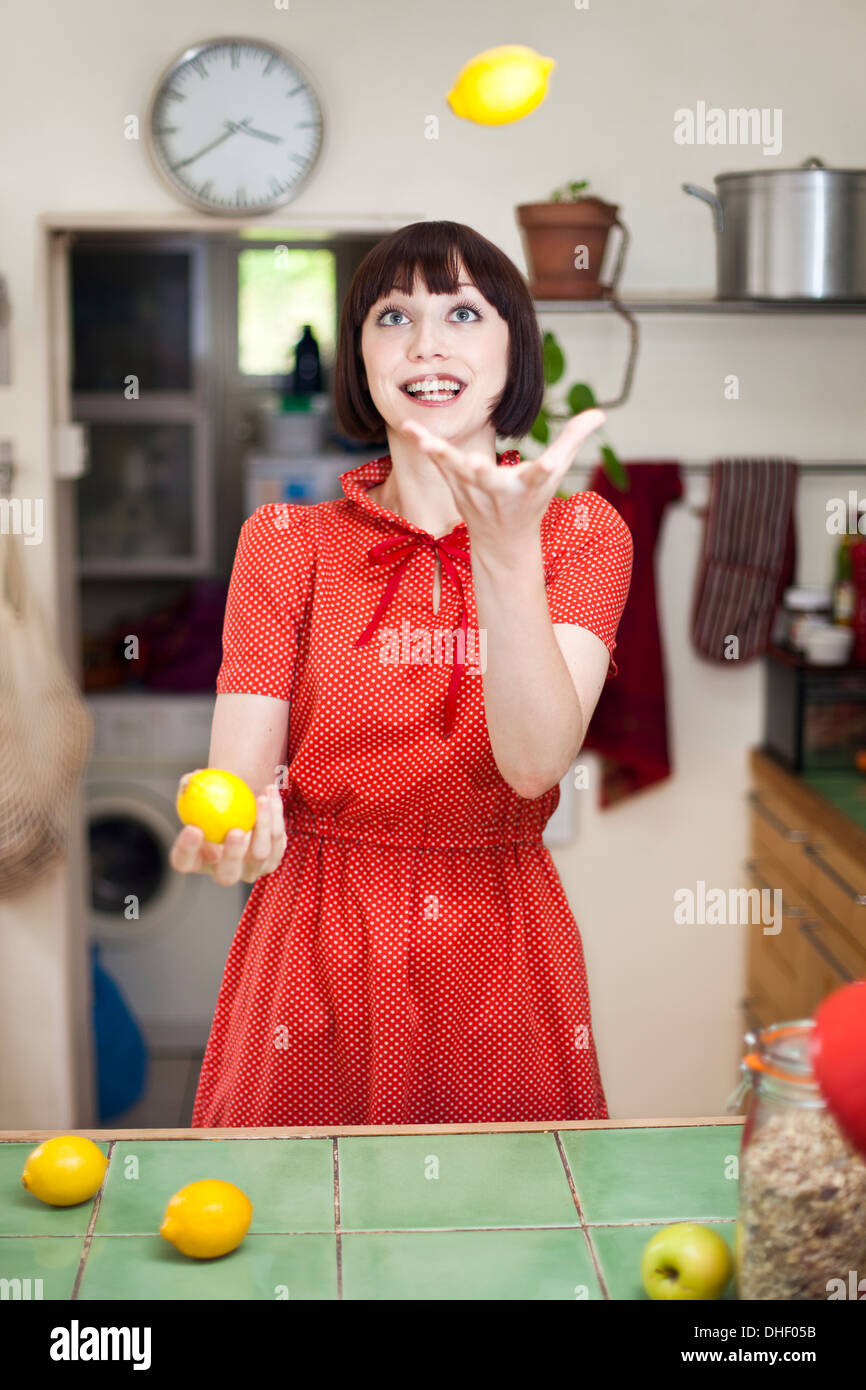 Junge Frau in der Küche jonglieren Zitronen Stockfoto