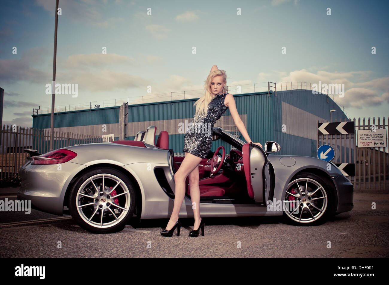 Junge blonde Modell in engen Kleid mit Porshe Supersportwagen Stockfoto