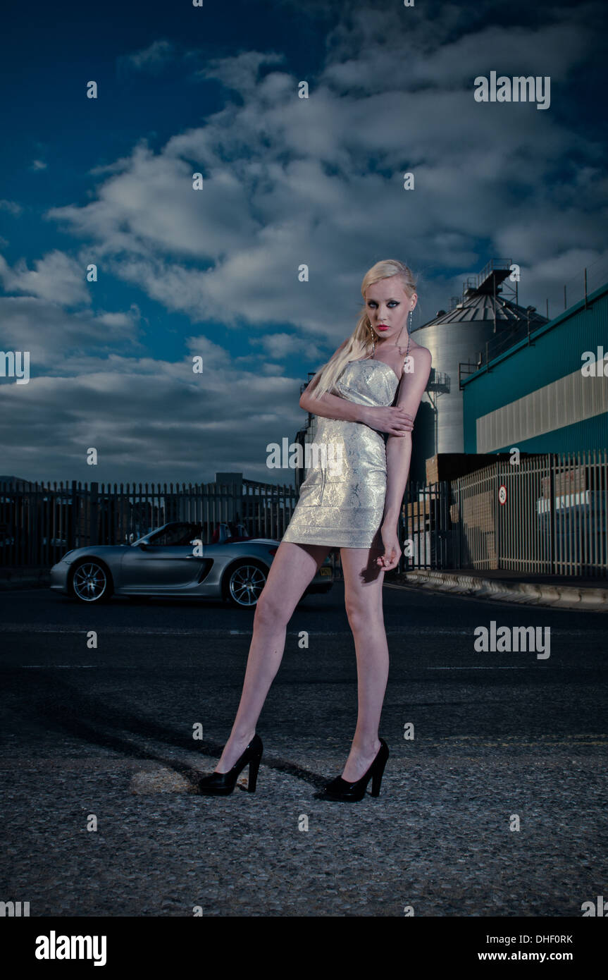 Junge blonde Modell in engen Kleid mit Porshe Supersportwagen Stockfoto