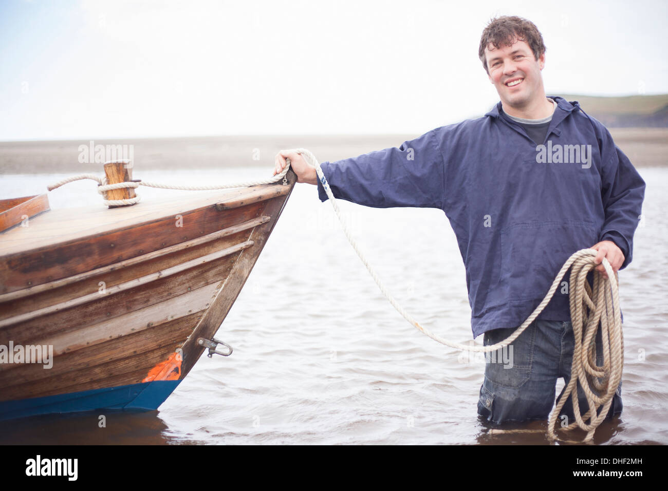 Porträt des Mannes halten Seil stützte sich auf Ruderboot, Wales, UK Stockfoto