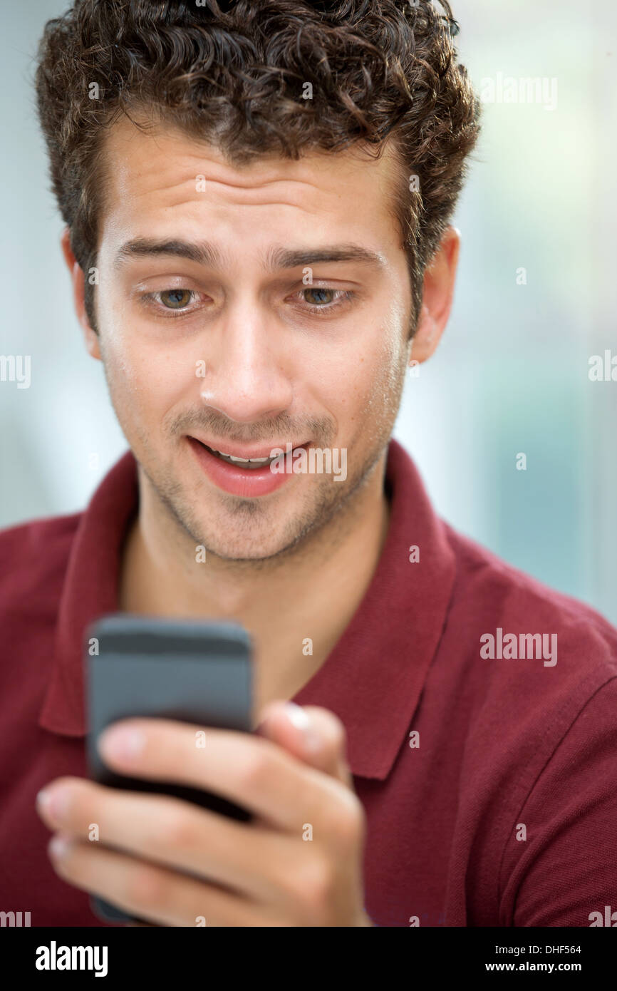 Junger Mann, Blick auf SMS auf Handy Stockfoto