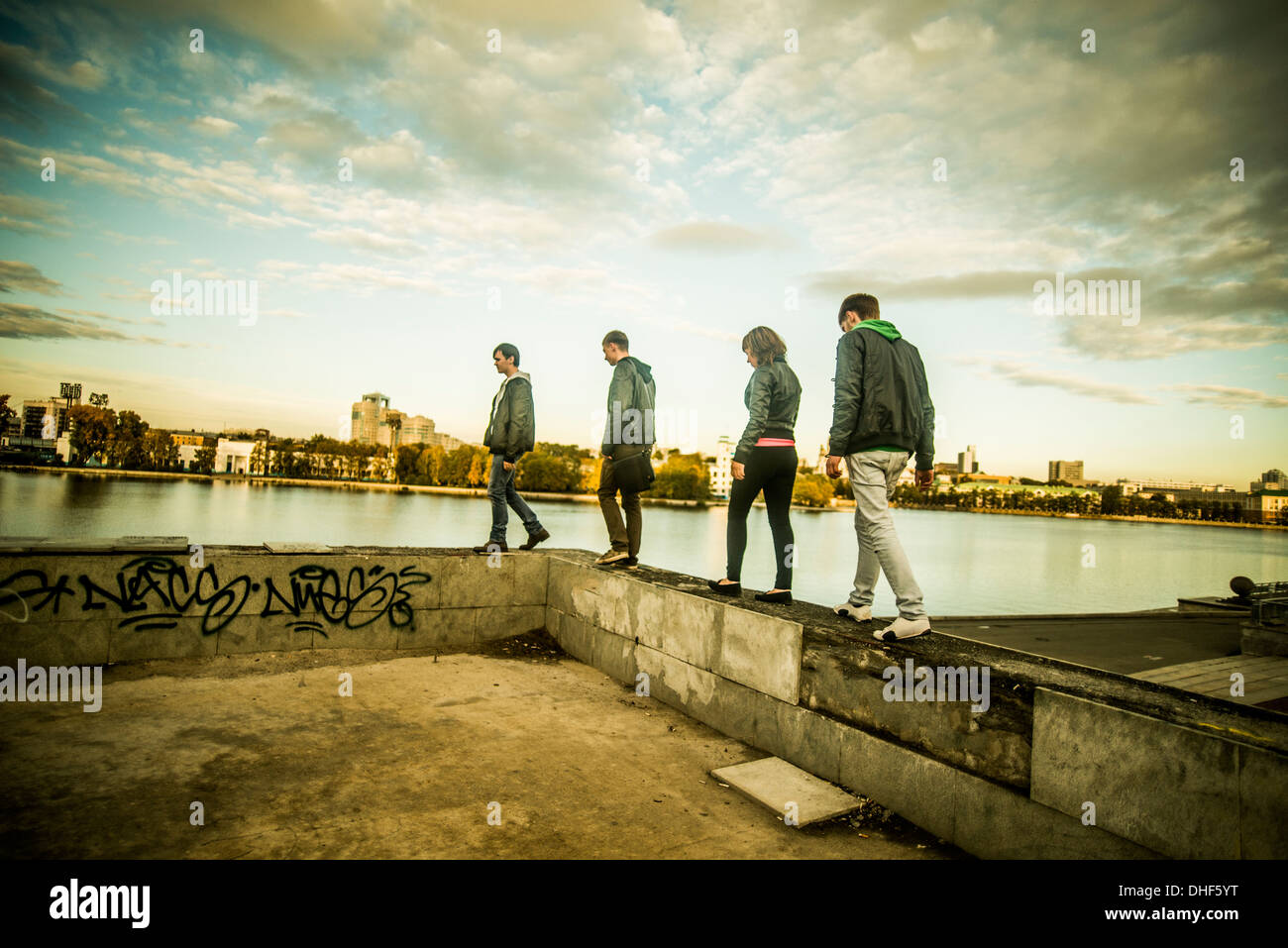 Vier Freunde, die zu Fuß entlang der Betonmauer, Russland Stockfoto