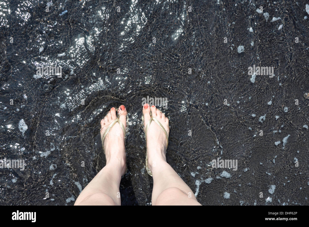 Füße im Meer aktiver Vulkan Vulkanasche Seesand schwarz Stockfoto