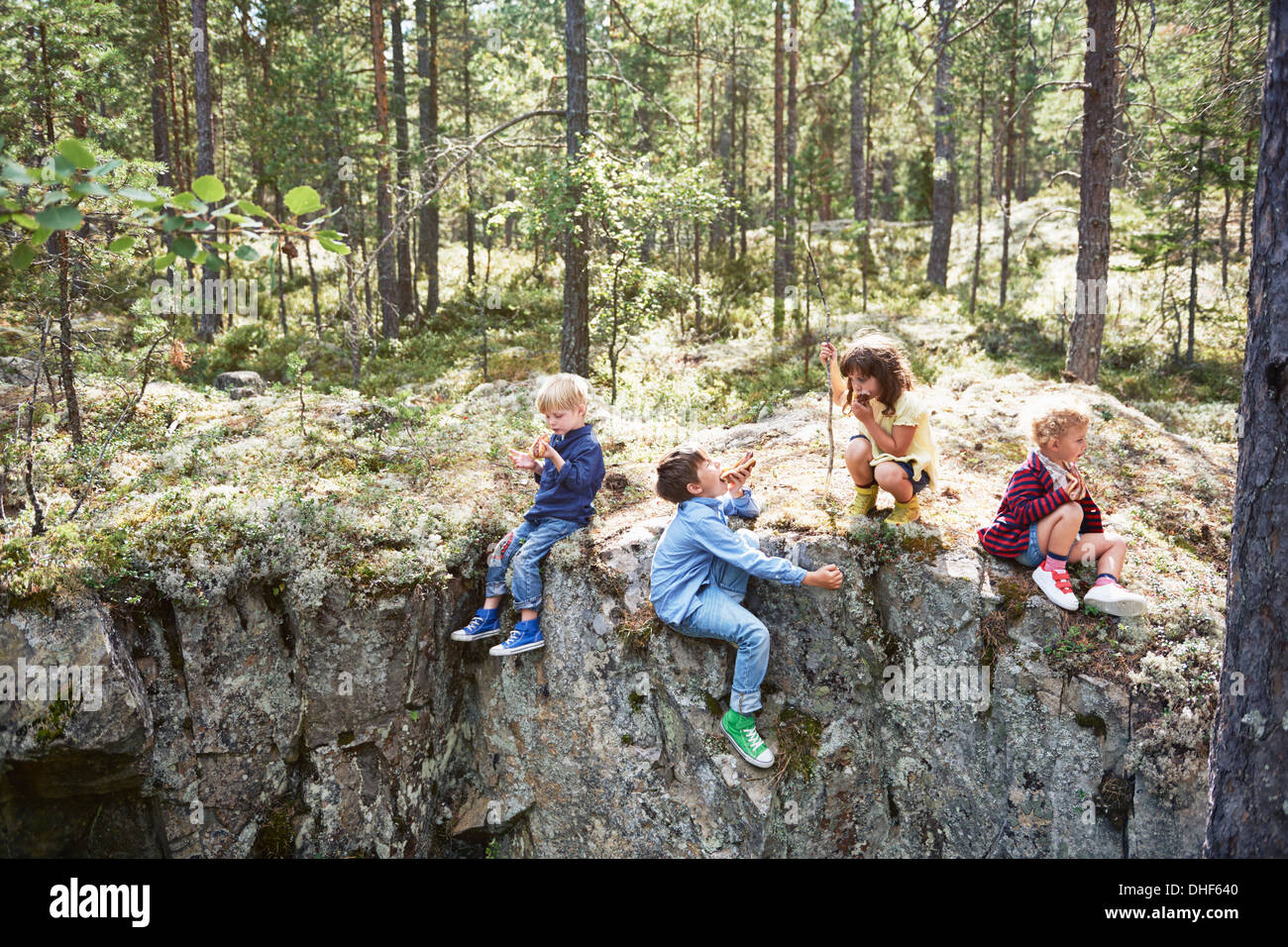 Kinder sitzen auf den Felsen im Wald Picknick Essen Stockfoto