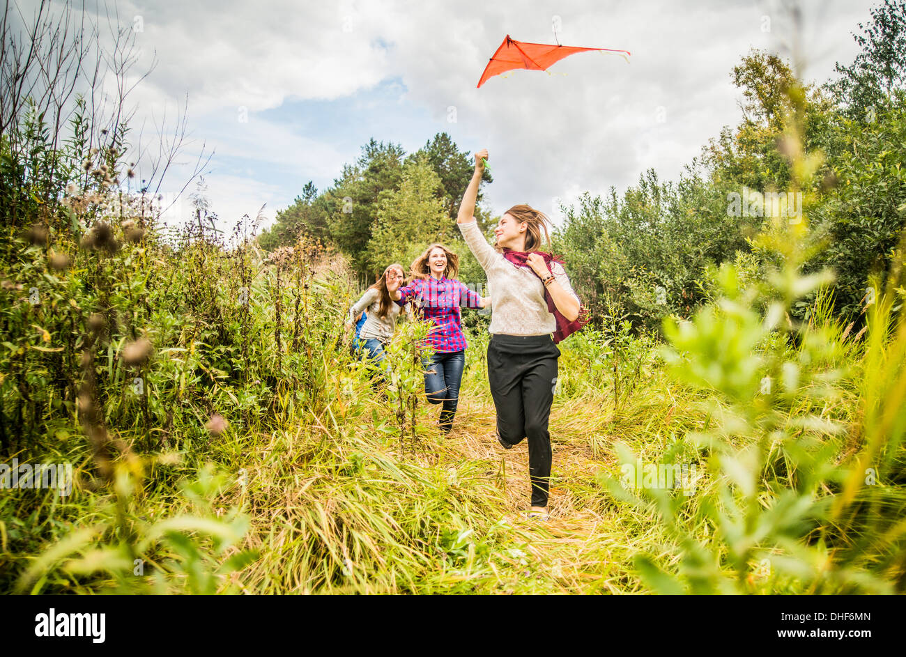 Vier junge Frauen laufen durch Buschland mit kite Stockfoto