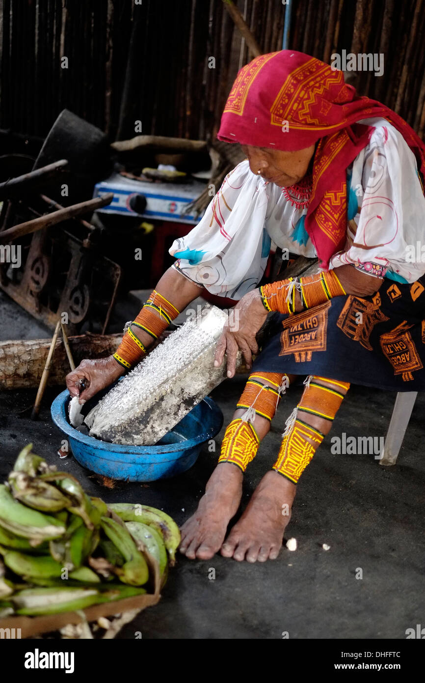 Eine indigene Guna-Frau in traditioneller Kleidung, die in ihrer Küche auf der Insel Carti Sugtupu in der Comarca (Region) der Guna Yala-Ureinwohner, bekannt als Kuna, frische Kokosnuss zerkleinert, die sich im Archipel der San Blas Blas-Inseln im Nordosten Panamas mit Blick auf das Karibische Meer befindet. Stockfoto