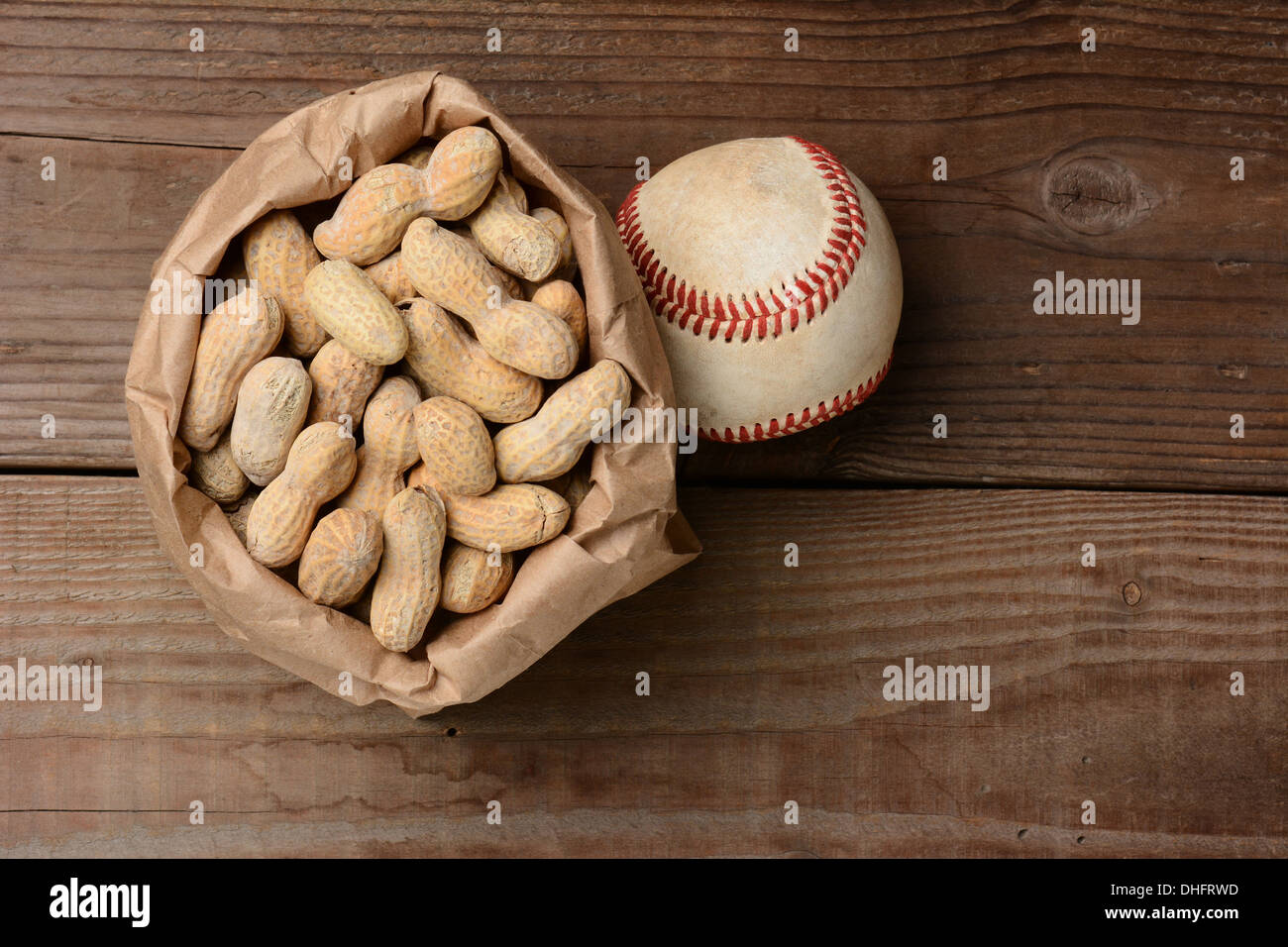 Eine Tasche von Erdnüssen und einen Baseball auf einer alten Holzbank im Stadion. Querformat mit Textfreiraum. Stockfoto