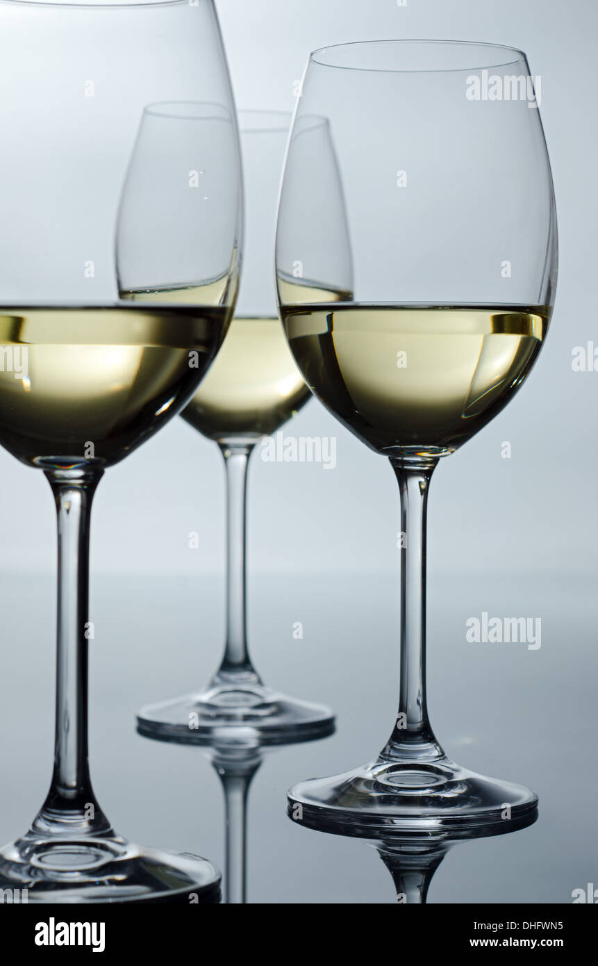 Hintergrundbeleuchtung, drei Gläser Wein auf einem Glastisch Stockfoto