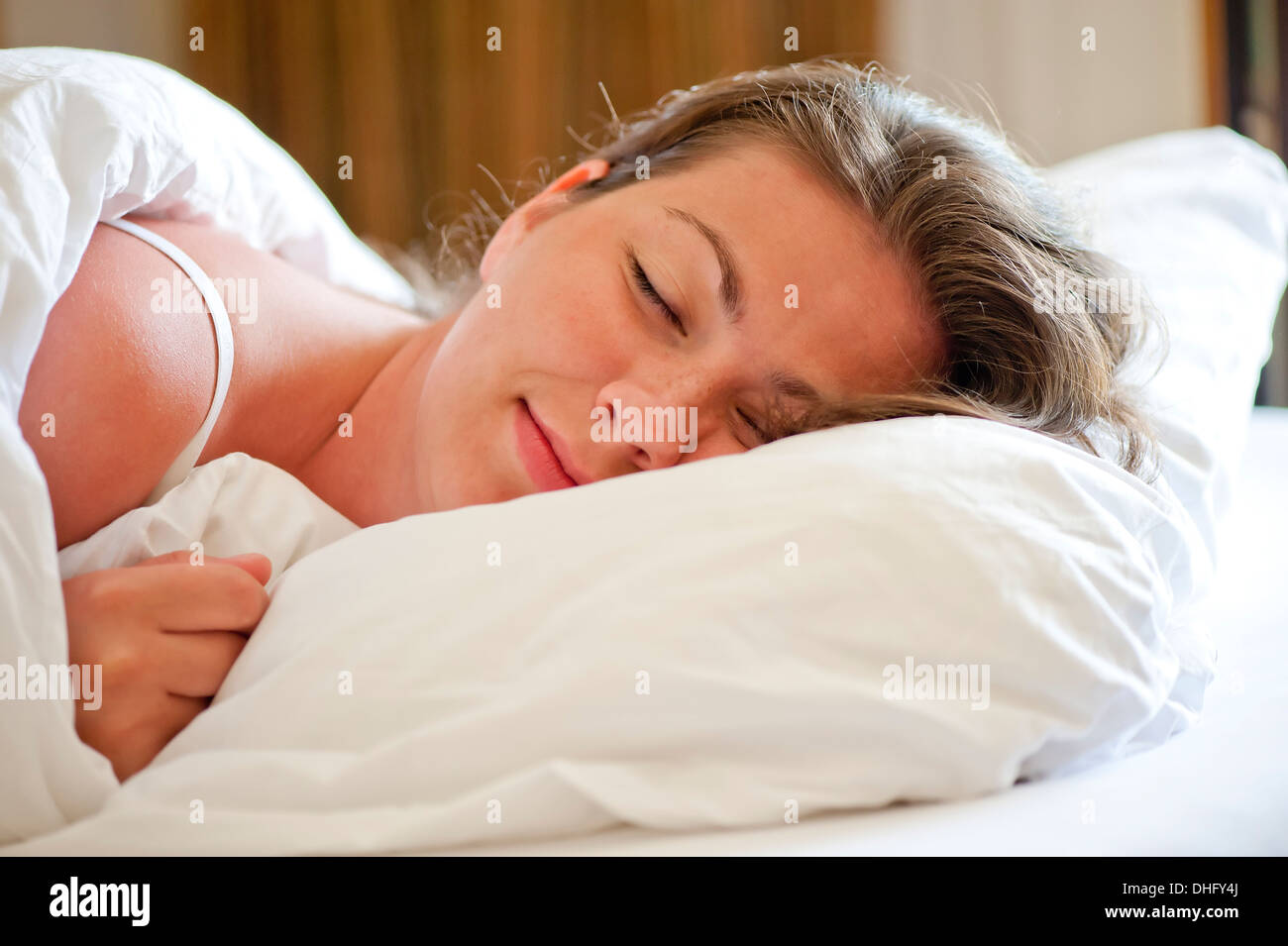 Frau schläft auf einem schneeweißen Bett am Morgen Stockfoto