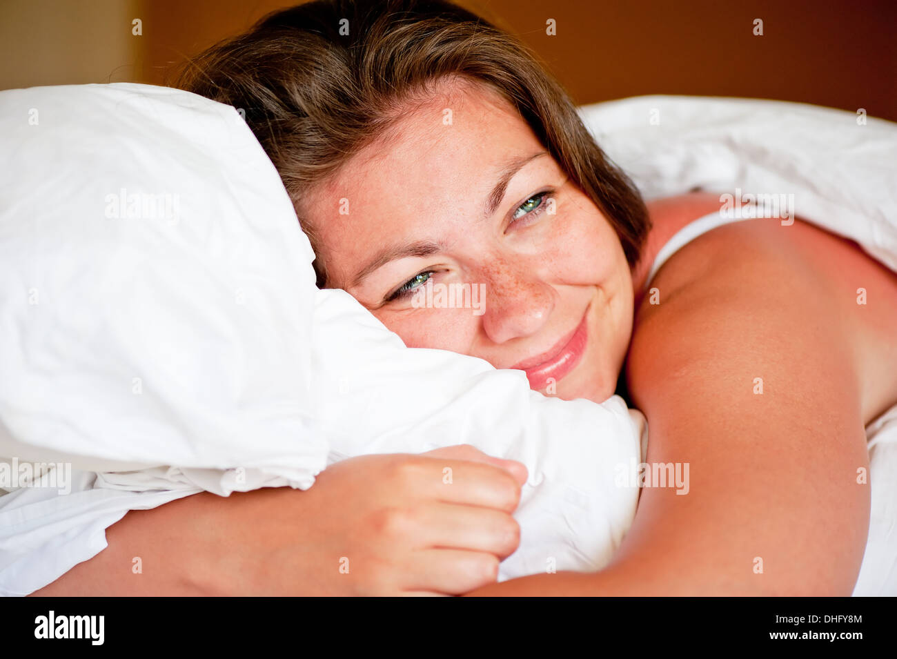 hübsches Mädchen im Bett mit einem Kissen Stockfoto