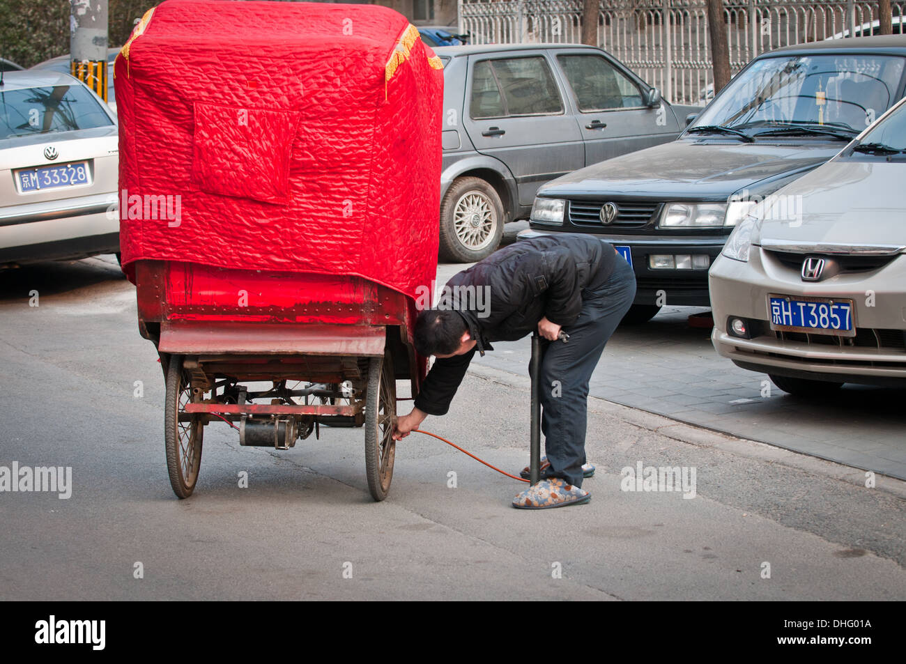 Rikscha-Fahrer Pumpen Rad auf Straße in Peking, China Stockfoto