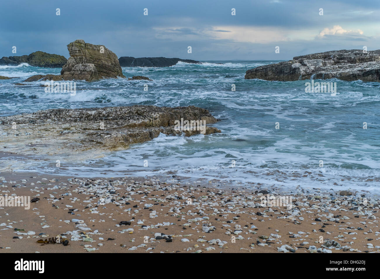 Strand-Szene in der Nähe von Ballintoy, mit Felsvorsprüngen in eine aufgewühlte Meer. Stockfoto