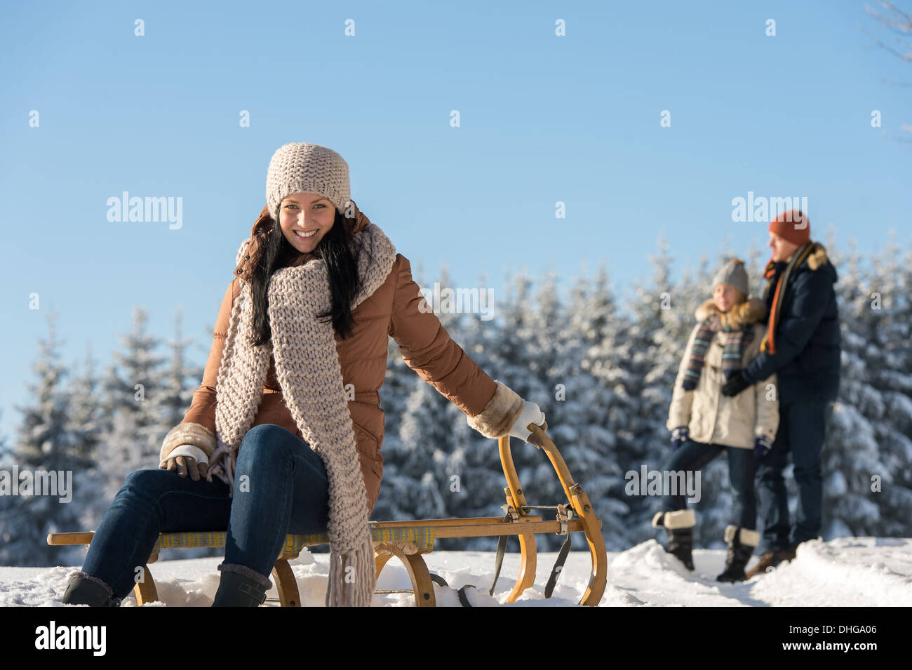 Junge Menschen genießen sonnige Winterschnee posiert auf Holzschlitten Stockfoto