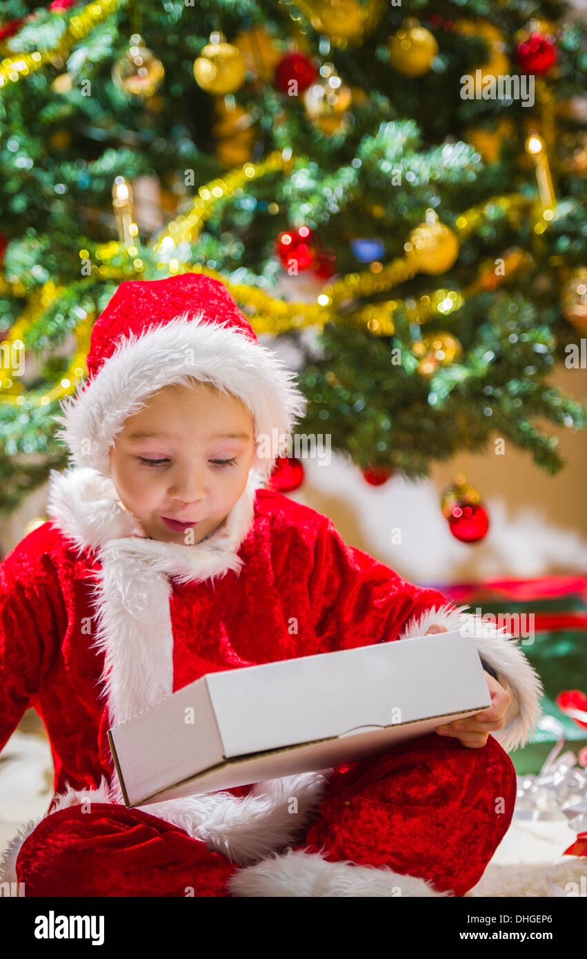 Überrascht junge öffnet ein Geschenk zu Weihnachten, Weihnachtsbaum und Geschenke auf Hintergrund Stockfoto