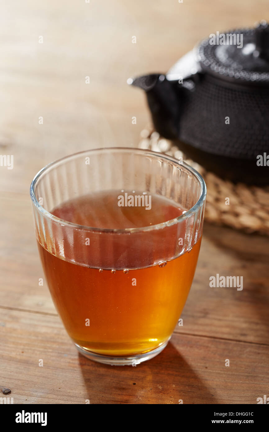 Brauner Tee auf Glasschale mit schwarzem Eisen Teekocher Stockfoto