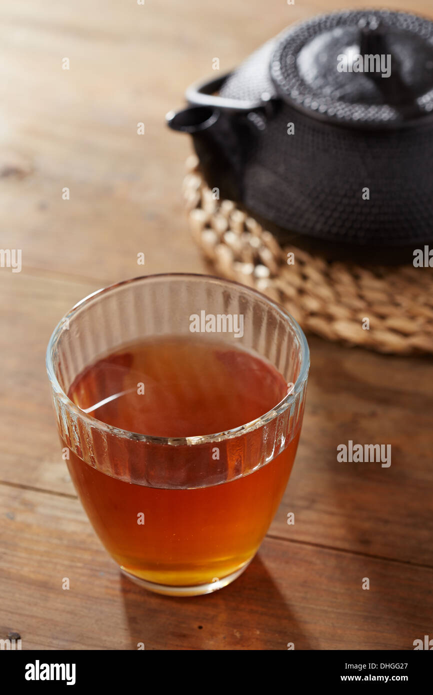 Brauner Tee auf Glasschale mit schwarzem Eisen Teekocher Stockfoto