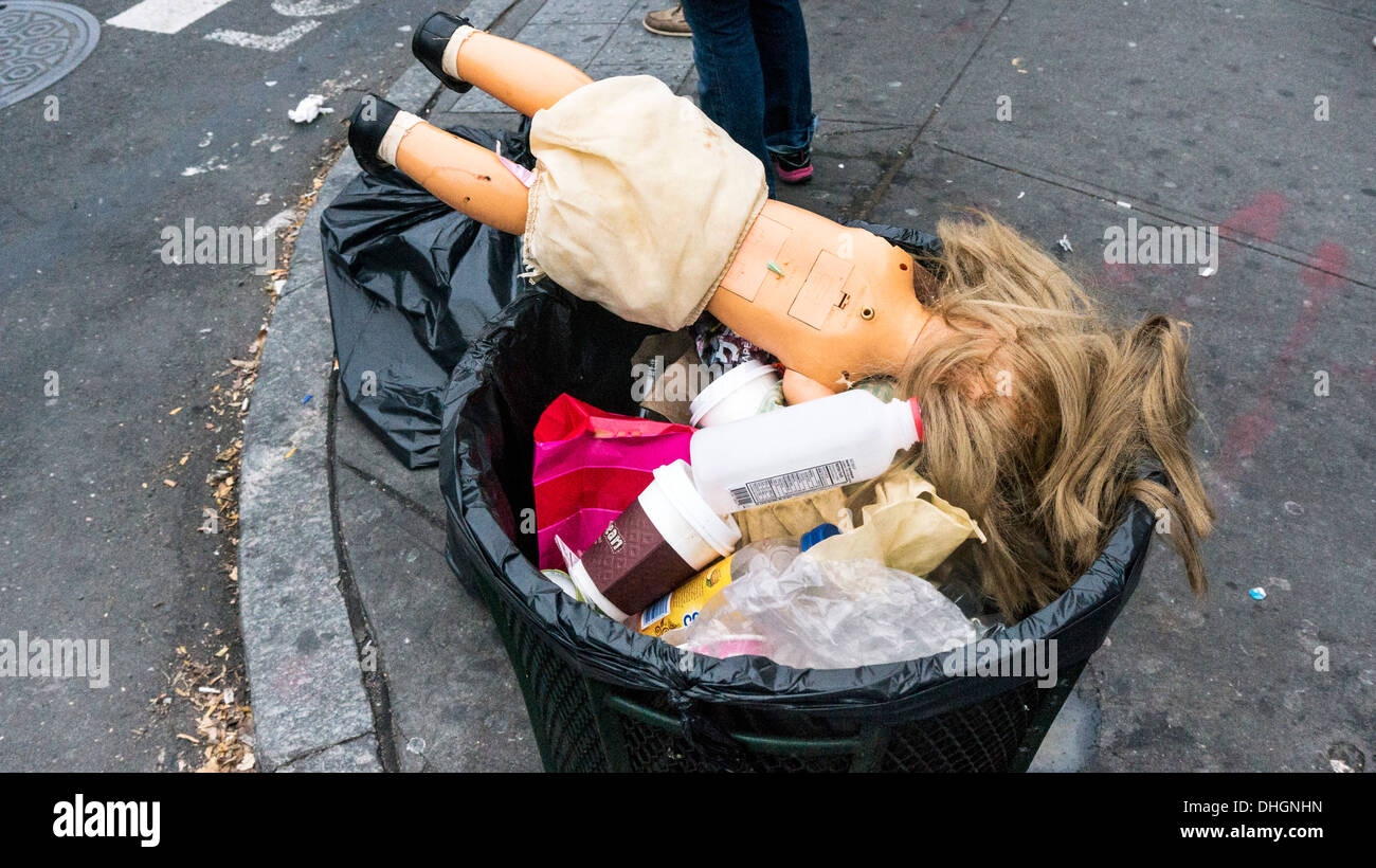 traurig goldenen Haaren Plastikpuppe aufgegeben in Abfalleimer mit Kaffeetassen & andere Detritus auf East Houston Street New York City Stockfoto