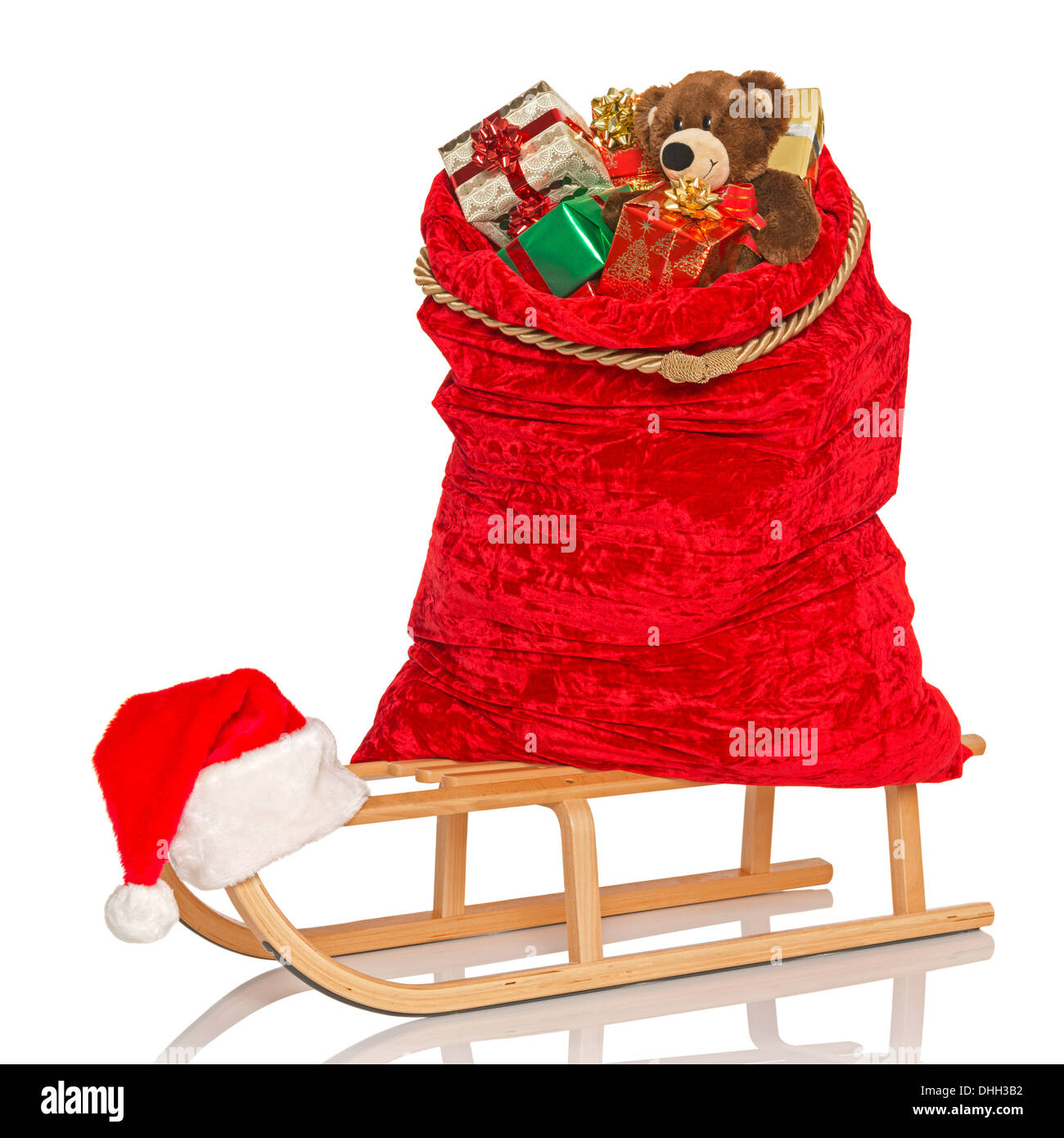 Santas Sack voller Geschenk verpackte Weihnachtsgeschenke und Spielzeug auf einem hölzernen Schlitten isoliert auf weißem Hintergrund. Stockfoto