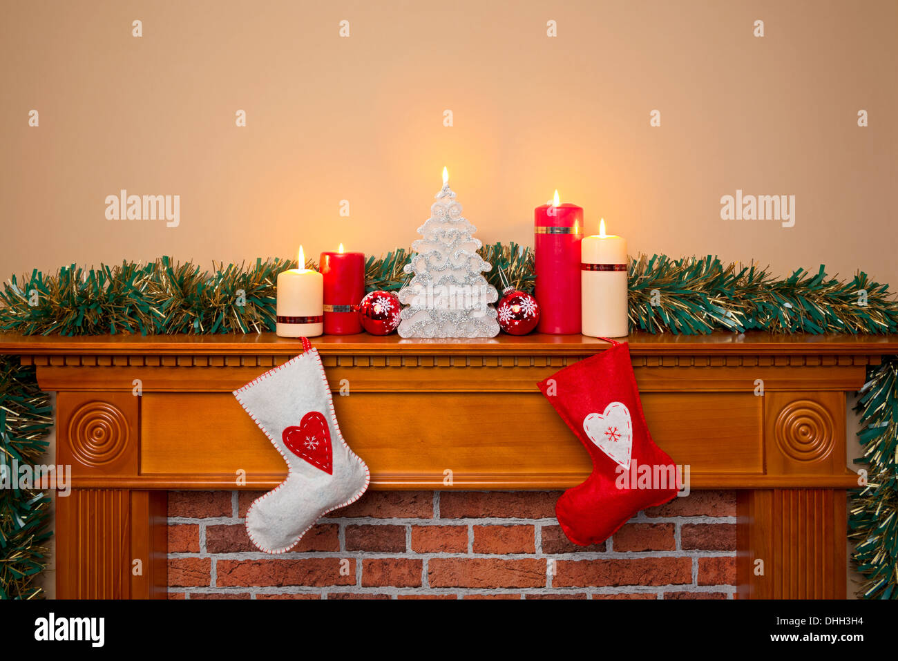 Weihnachtsstrümpfe schwebt über einem offenen Kamin mit Kerzen auf dem Kaminsims Stockfoto