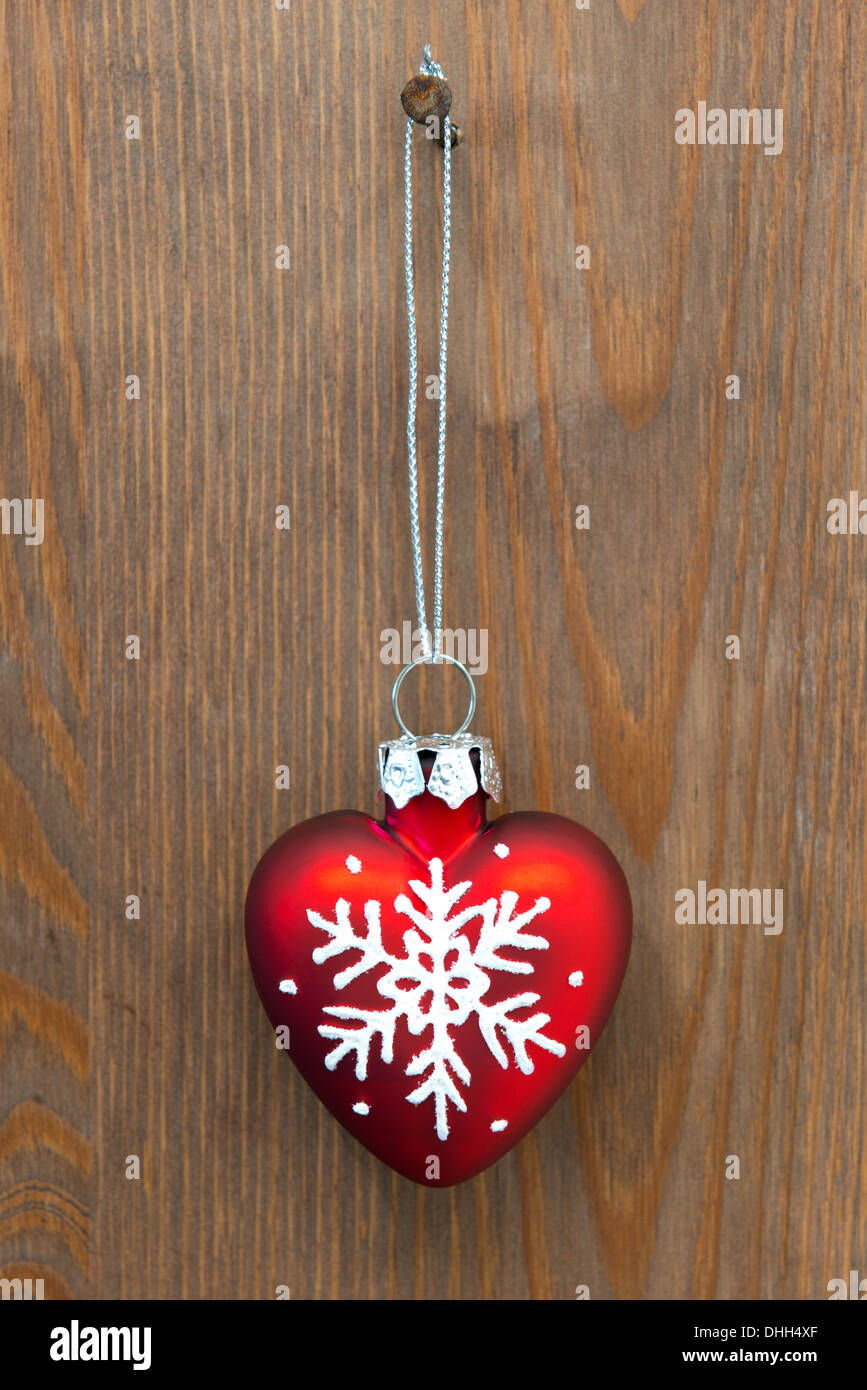 Rotes Herz geformt Christbaumschmuck hängen von einem rostigen Nagel an einer alten Holztür Stockfoto