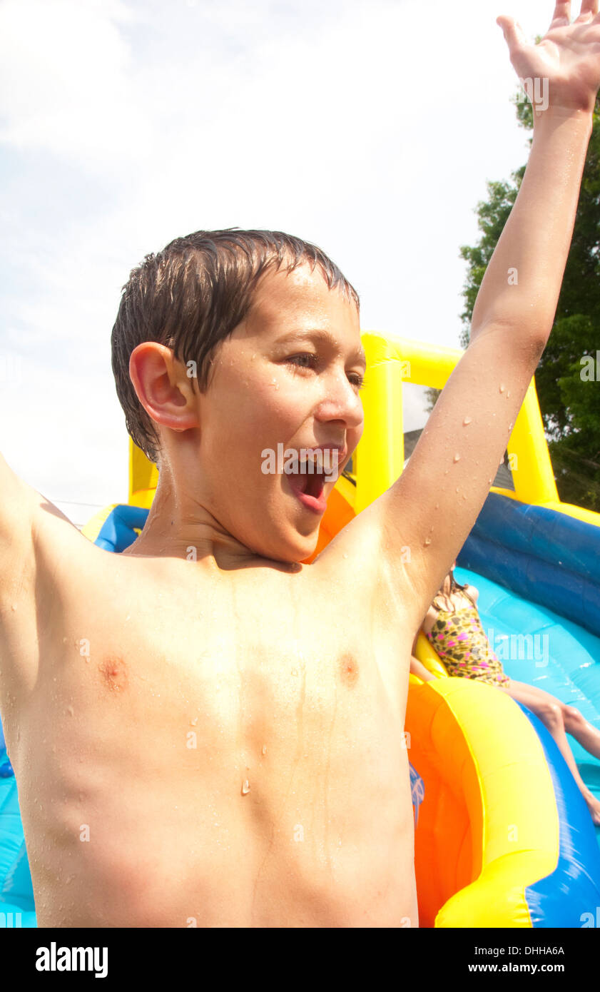 Familie Wasserrutsche im Hinterhof zu Hause mit Wasser im Sommer junge glücklich und Spaß 10 Jahre Stockfoto