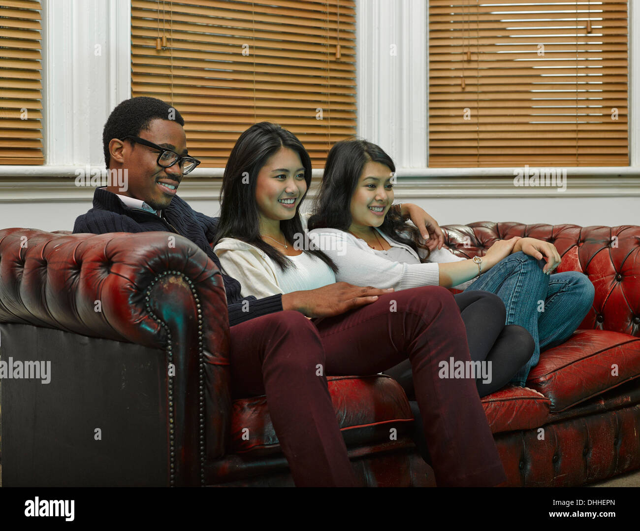 Drei junge Erwachsene Freunde Zusammensitzen auf sofa Stockfoto