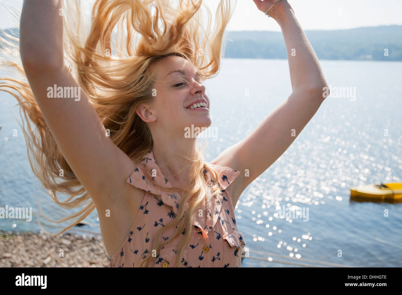 Porträt der jungen Frau mit langen blonden Haaren und erhobenen Armen Stockfoto