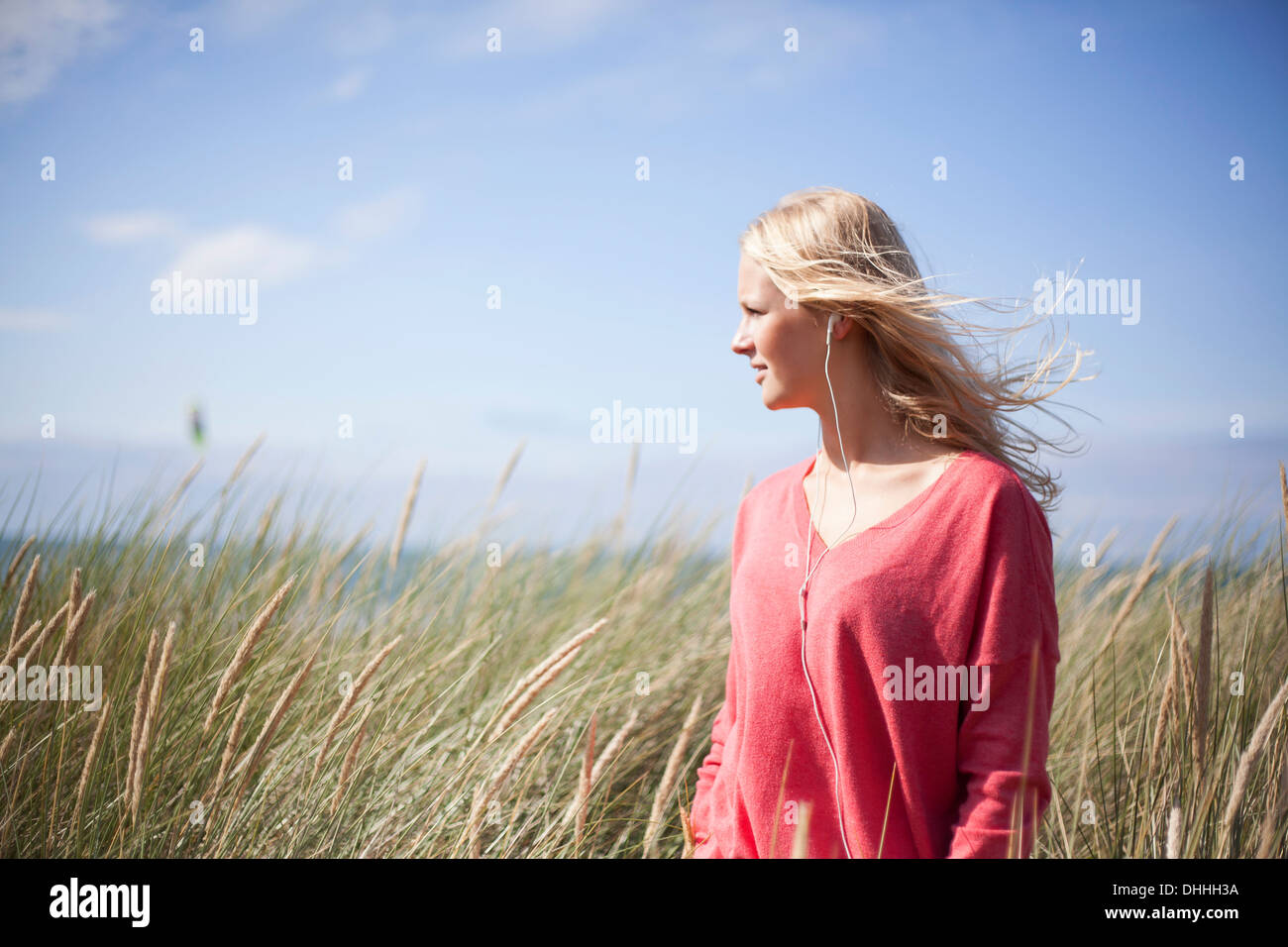 Porträt von blonde Frau trägt rosa Pullover in Dünengebieten Grass, Wales, UK Stockfoto