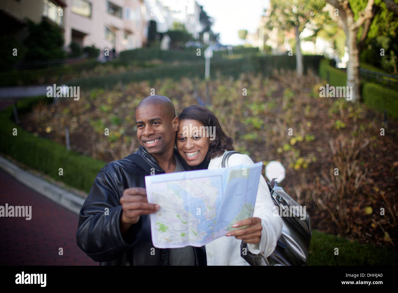 Paar attraktive schwarze Touristen in den Dreißigern navigieren curviest Straße in San Francisco mit einem alten Papierkarte und Moxie. Stockfoto